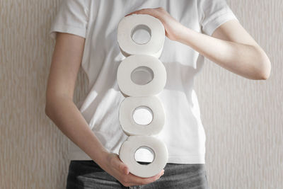 Midsection of man holding camera while standing against white wall at home