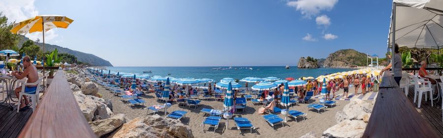 Panoramic view of people at beach against sky