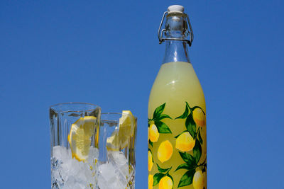 Close-up of glass bottle against blue sky