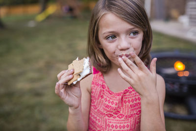 Girl looking away while eating smore at yard