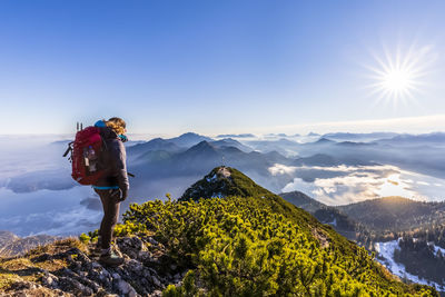 Germany, bavaria, female hiker admiring surrounding landscape from summit of herzogstand mountain