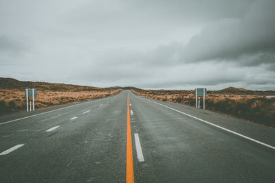 Empty road against cloudy sky