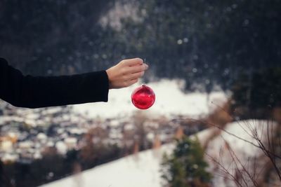 Cropped hand holding red bauble during winter