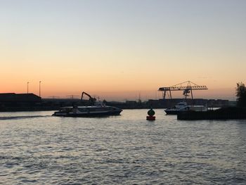 Silhouette sailboats in sea against clear sky during sunset