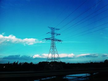 Electricity pylon on field against blue sky