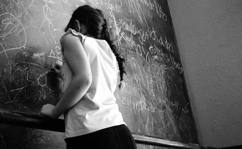 Rear view of girl drawing on blackboard