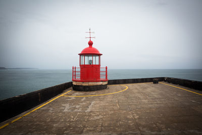 Lighthouse by sea against sky