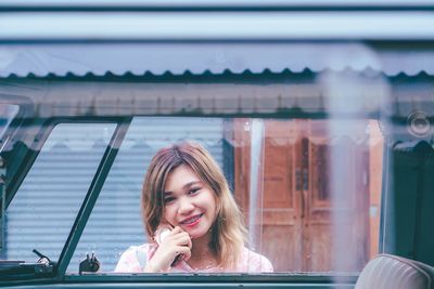 Portrait of smiling young woman seen through car window