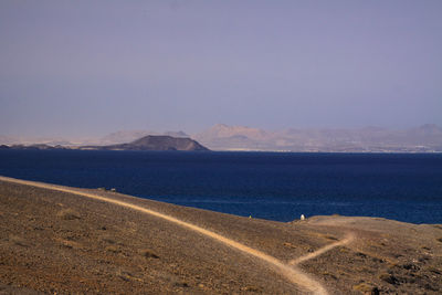 Scenic view of road by sea against sky