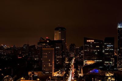 Illuminated buildings in city against sky at night