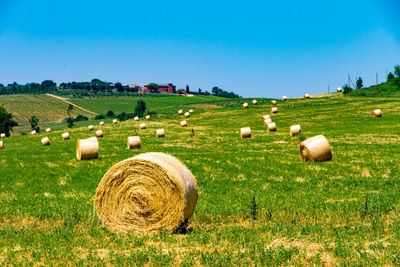 Hay bales on field against clear sky