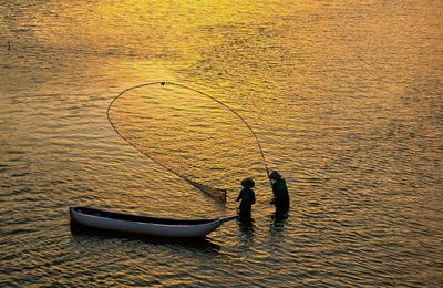 High angle view of men fishing in sea during sunset