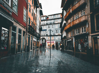 Wet street amidst buildings in city during rainy season