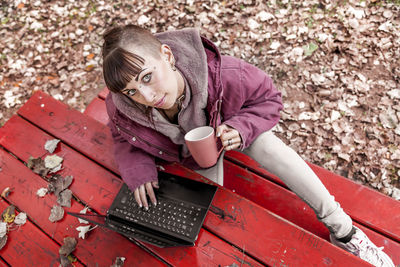 High angle portrait of young woman using laptop on table while sitting in park