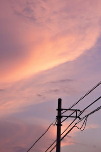 Low angle view of silhouette electricity pylon against dramatic sky