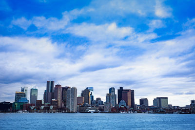 Sea by modern buildings against sky in city