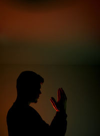 Silhouette young man gesturing while standing in darkroom