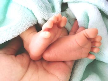 Cropped image of mother holding baby feet wrapped in towel