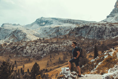 Man standing on rock against sky