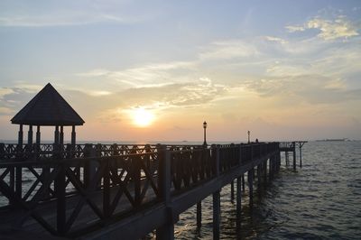 Pier over sea against sky during sunset