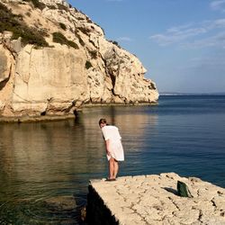 Man standing on rock formation in sea