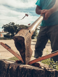 Midsection of man cutting tree trunk