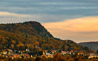 Trees and houses against sky during autumn