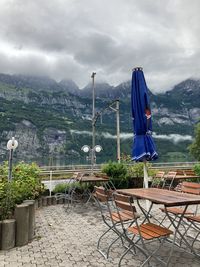 Chairs and table against mountain range against sky