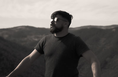 Man in sunglasses standing against mountain