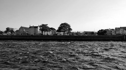 Buildings by sea against clear sky