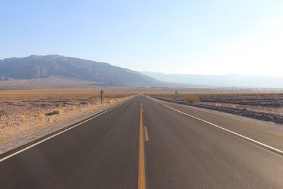 Road leading towards mountains against sky