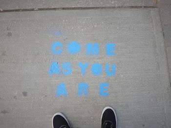 Low section of person standing on road sign