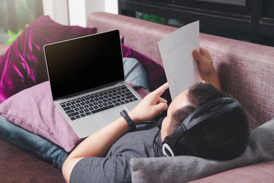 Rear view of woman using mobile phone at home