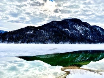 Scenic view of lake by snowcapped mountains against sky