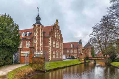 Buildings by river against sky