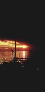 Silhouette sailboat in sea against sky during sunset