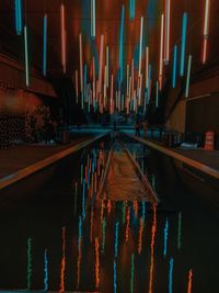 Panoramic shot of illuminated road by building against sky at night