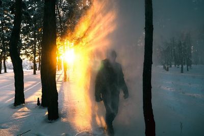 Man on snow covered landscape against sky during sunset