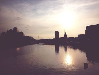 Sunset over river with buildings in background