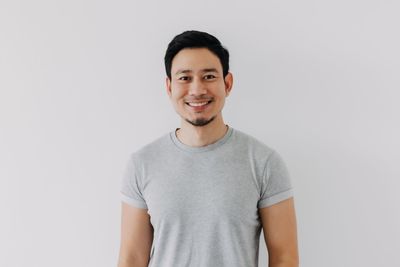 Portrait of young man standing against white background