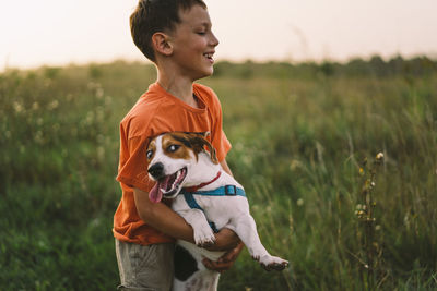 Portrait of a little boy playing with his jack russell dog in the park.