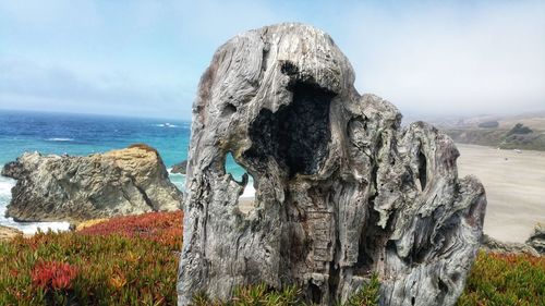 Rock formation on beach against sky