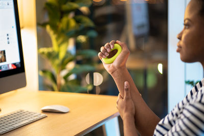 African american woman deals with prevention of carpal tunnel syndrome using expander while working