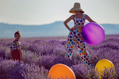 Woman in suit with multicolored polka dots ,hat in lavender field with child in multicolored costume