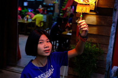 Portrait of young woman holding lantern at night