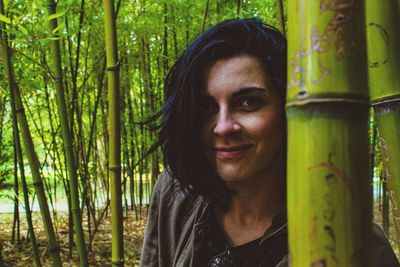 Portrait of young woman smiling while standing in bamboo grove