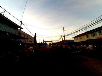 People on street in city against sky at sunset