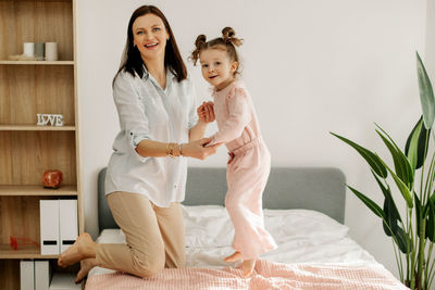 Portrait of young woman sitting on bed at home