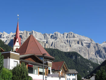 Houses by mountains against clear blue sky