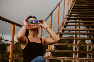 Young woman in sunglasses sitting against steps